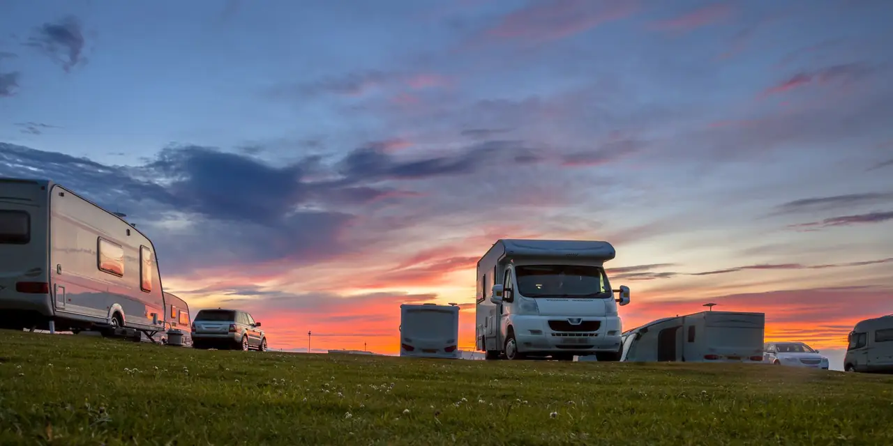 Motorhomes and touring caravans on a campsite at sunset