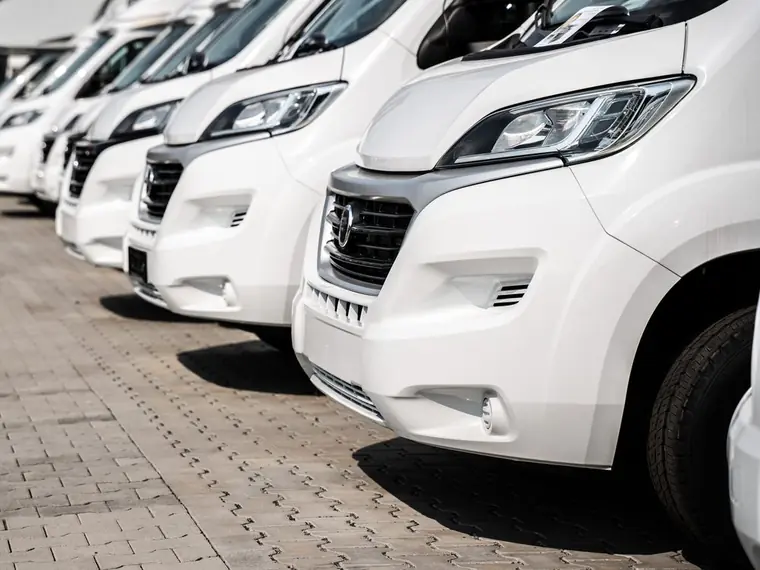 Row of white motorhomes parked on a forecourt